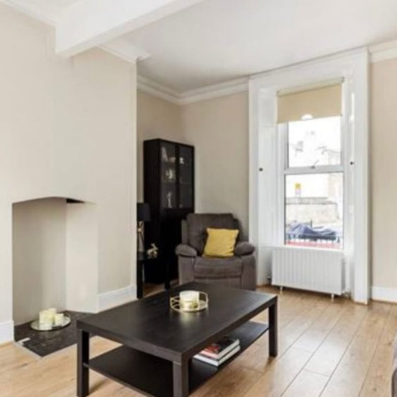 Living room interior with dark coffee table, armchair, and fireplace.