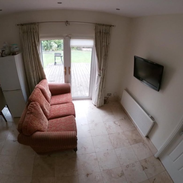 Living room with red sofa, TV, radiator, and patio doors to garden.