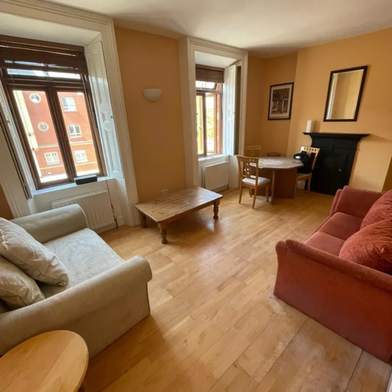 Cozy living room with sofa, coffee table, dining set, and fireplace.