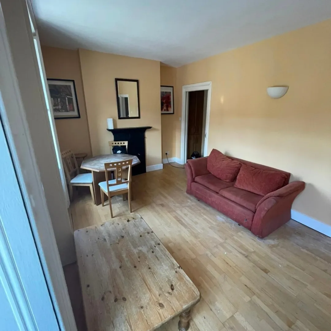 Cozy living room with sofa, dining table, and light hardwood floors.