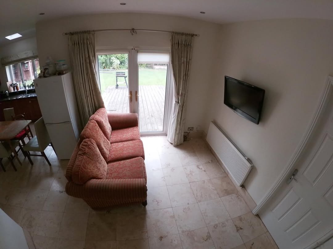 Living room with sofa, TV, radiator, and patio doors leading to a garden.