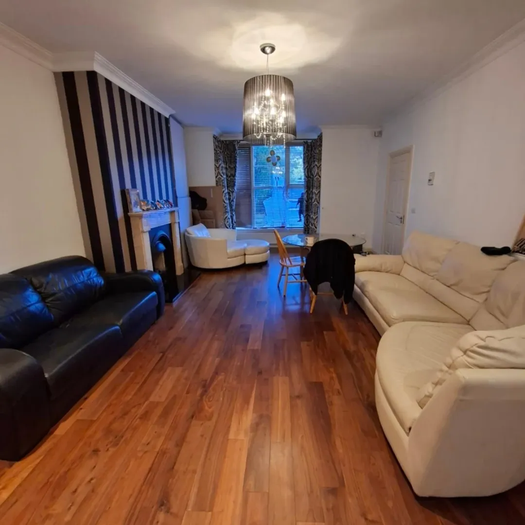 Living room with sofas, fireplace, chandelier, and hardwood floors.