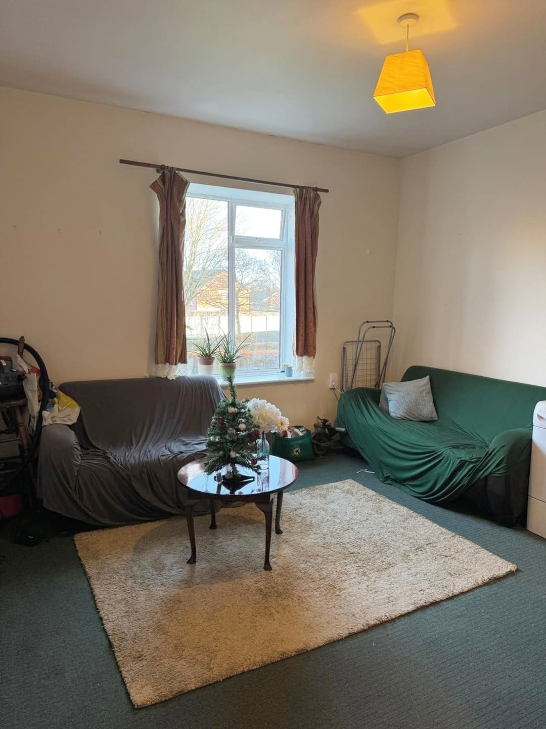 Living room with sofas, rug, coffee table, and window. Neutral color scheme.