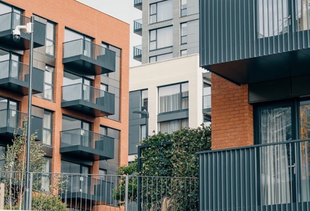 Modern apartment buildings with balconies and brick facade in an urban setting.