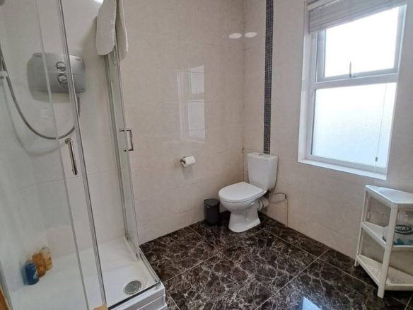 Modern bathroom with shower, toilet, and marble floor tiles.