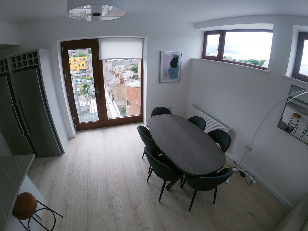 Modern dining area with oval table, green chairs, and balcony access.