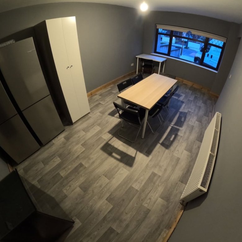Modern dining area with table, chairs, refrigerators, and a window view.