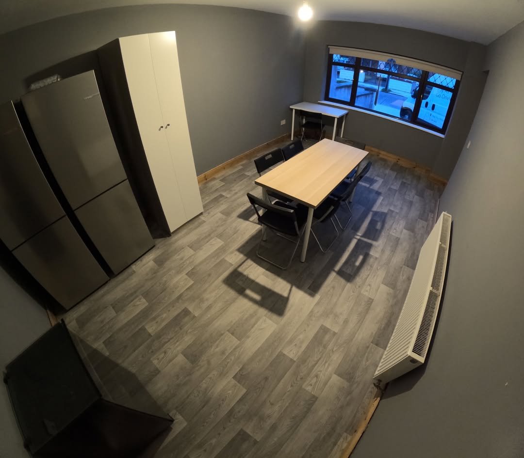 Modern dining area with table, chairs, refrigerators, and a window view.