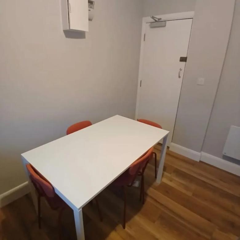 Dining area with white table and orange chairs in a modern room.