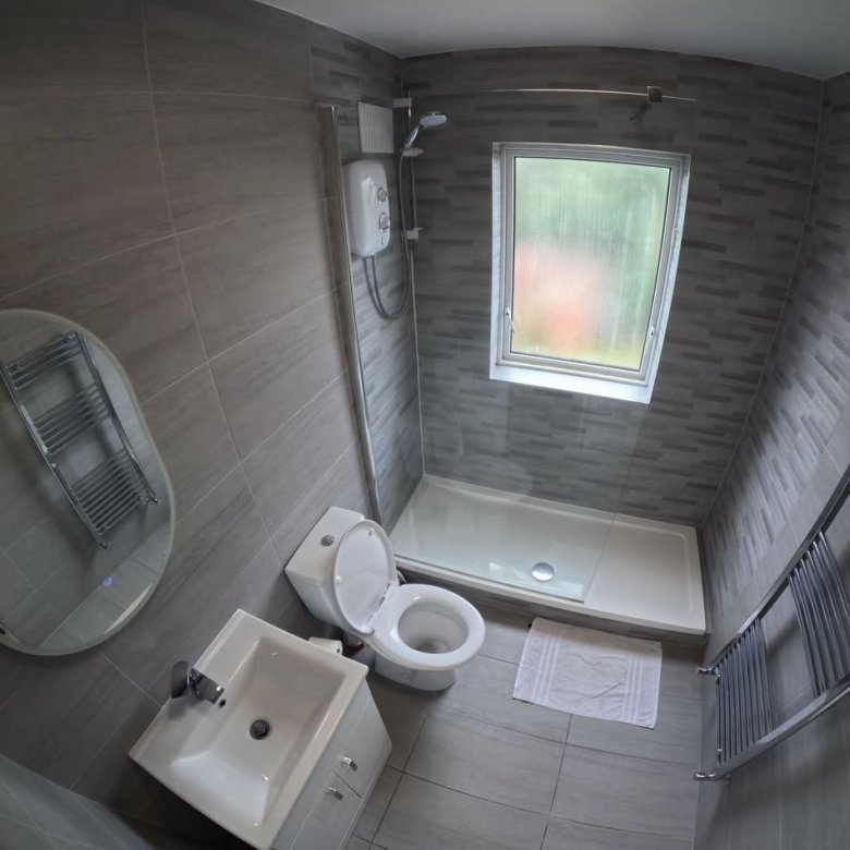 Modern gray bathroom with toilet, sink, shower, and heated towel rack.