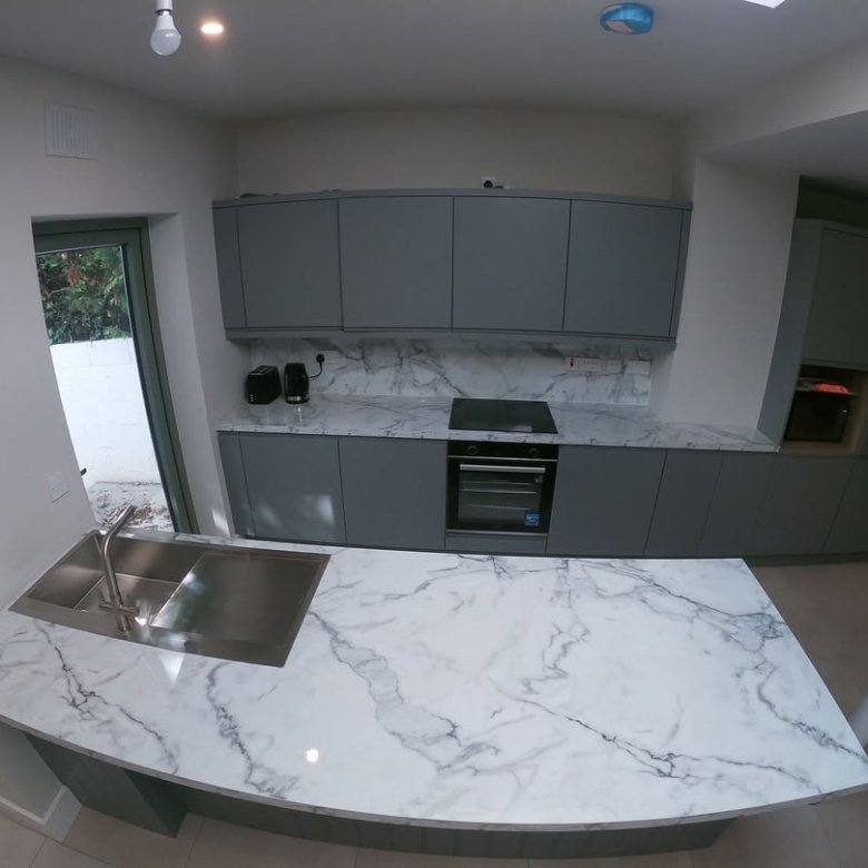 Modern gray kitchen with marble countertop island and stainless steel sink.