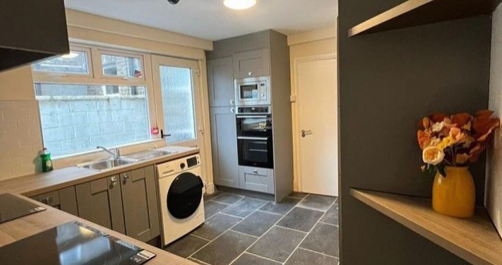 Modern kitchen with gray cabinets, slate tile floor, and stainless steel appliances.