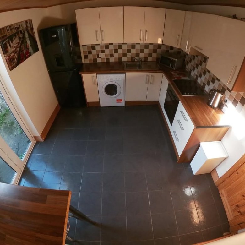 Modern kitchen with black appliances, white cabinets, and dark gray tile flooring.