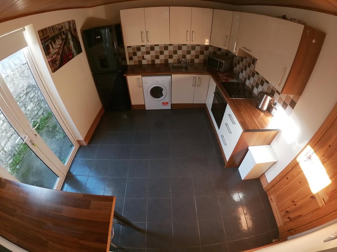 Modern kitchen with black appliances, white cabinets, and dark gray tile flooring.