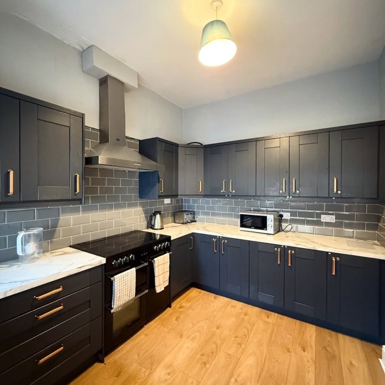 Modern kitchen with dark cabinets, marble countertops, and wood floors.