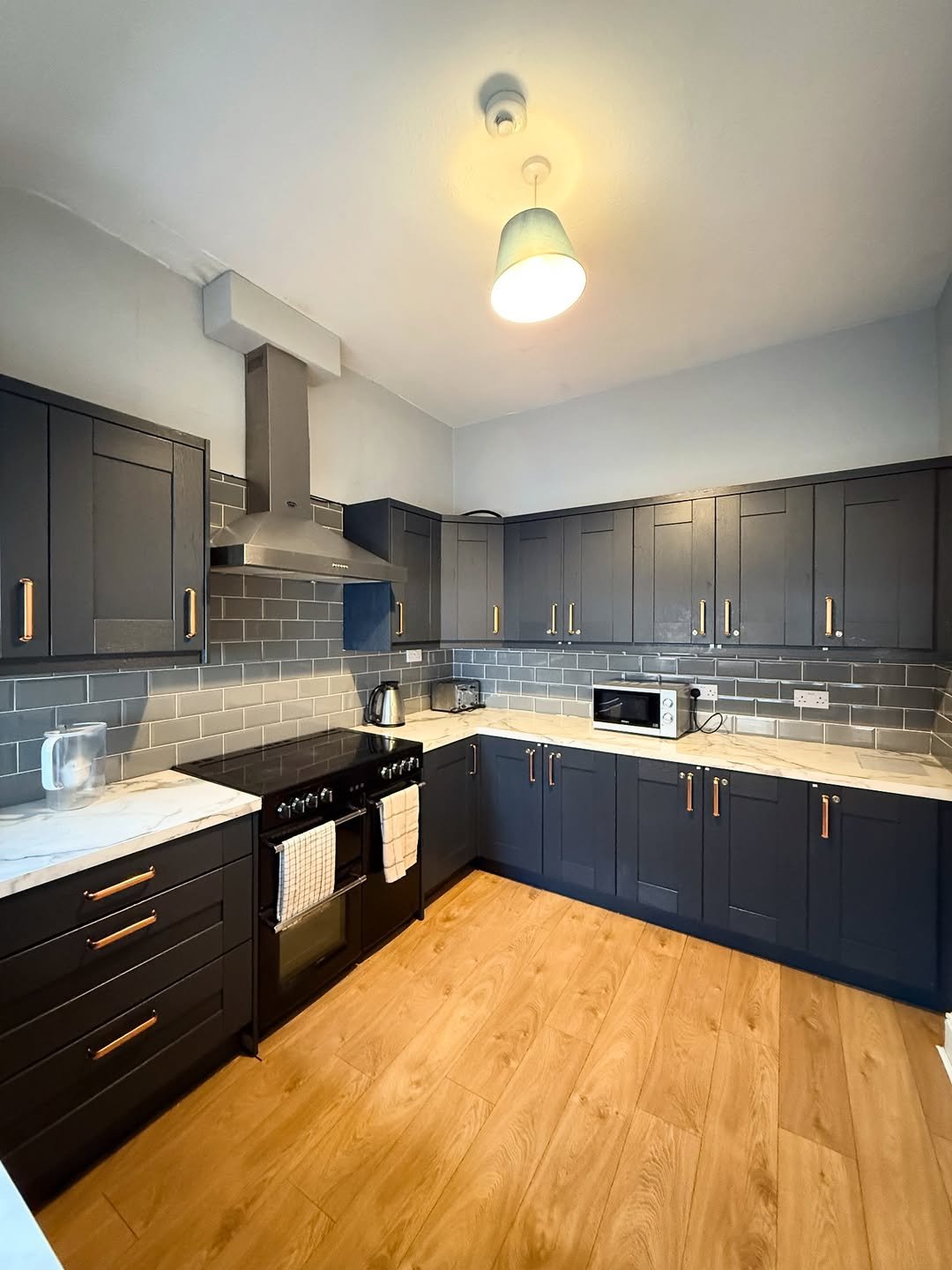 Modern kitchen with dark cabinets, marble countertops, and wood floors.