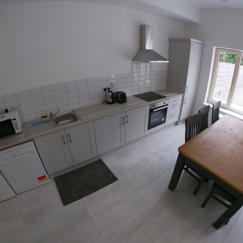 Modern kitchen with gray cabinets, stainless steel appliances, and dining table.