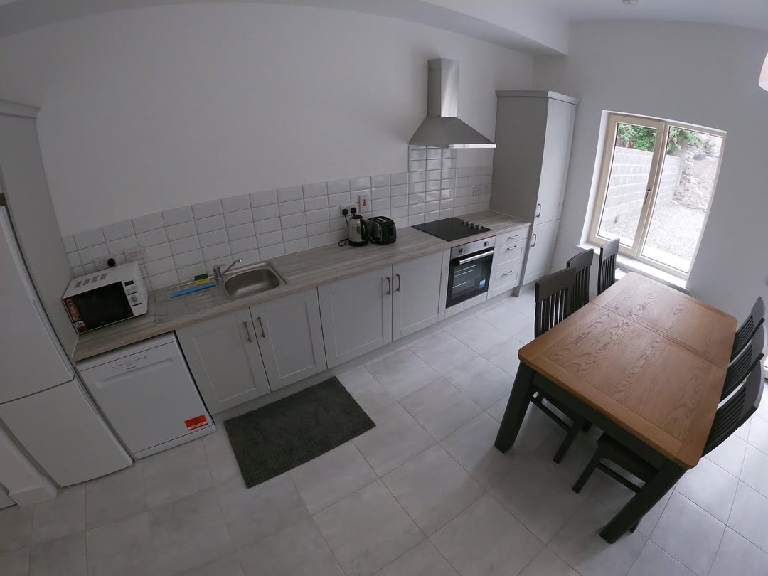 Modern kitchen with gray cabinets, stainless steel appliances, and dining table.