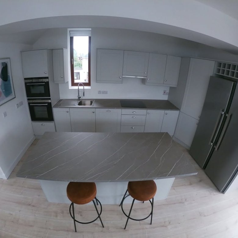 Modern kitchen with island, gray cabinets, and stainless steel appliances.