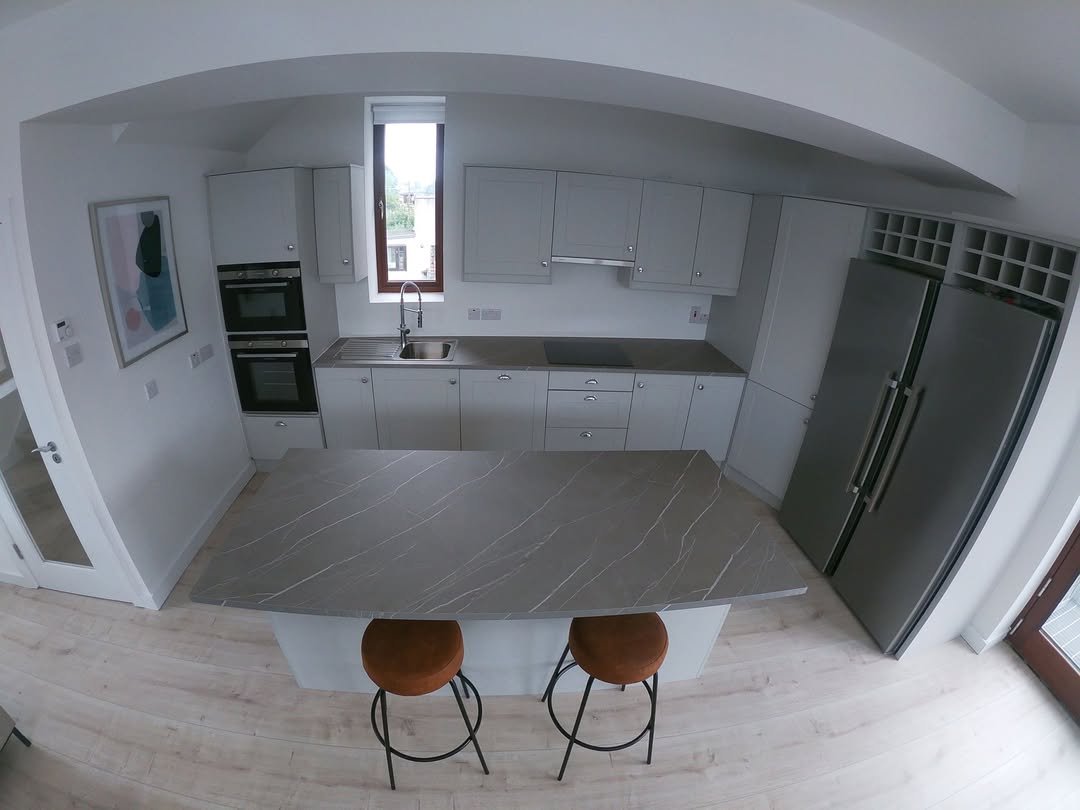 Modern kitchen with island, gray cabinets, and stainless steel appliances.