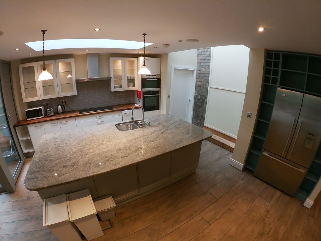 Modern kitchen interior with large island, stainless steel appliances, and skylight.