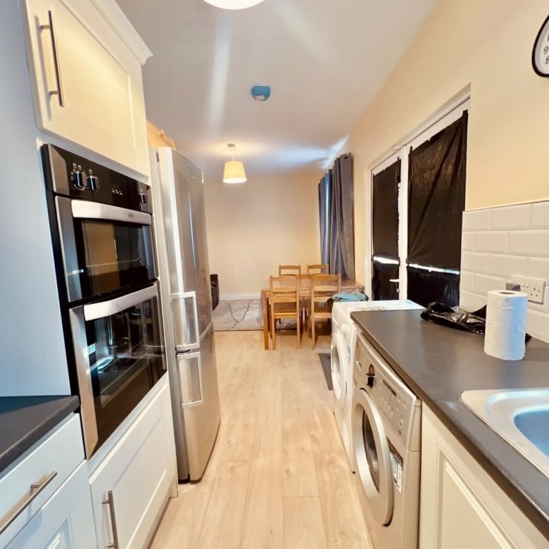 Modern kitchen interior with stainless steel appliances and light wood floors.