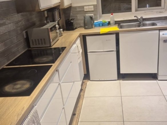 Modern kitchen with white cabinets, wood countertops, and tile backsplash.