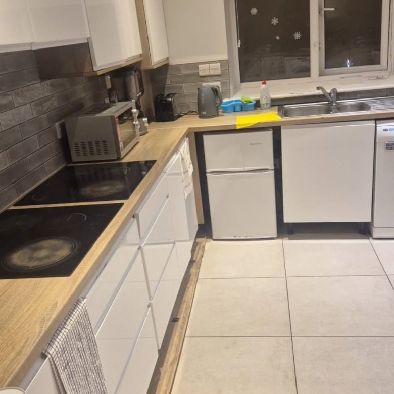 Modern kitchen with white cabinets, wood countertops, and tile backsplash.