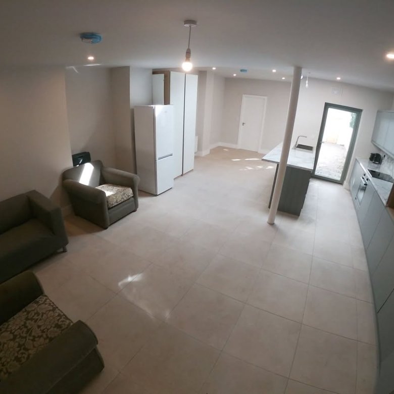 Bright, modern open-plan kitchen and living area with gray cabinets and seating.