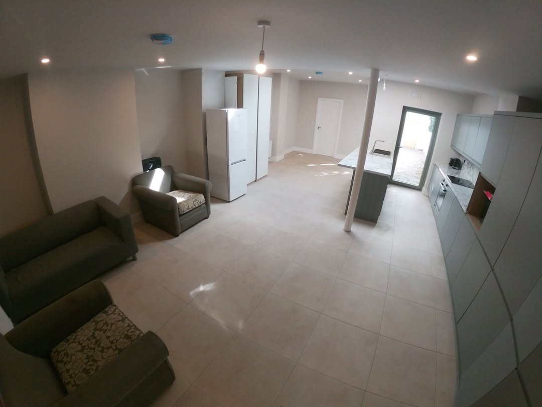 Bright, modern open-plan kitchen and living area with gray cabinets and seating.