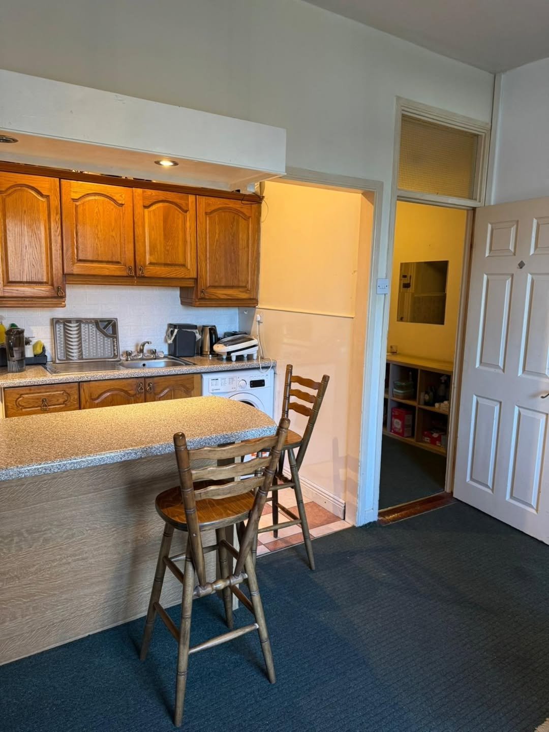 Kitchen with oak cabinets, breakfast bar, and stools near doorway to another room.