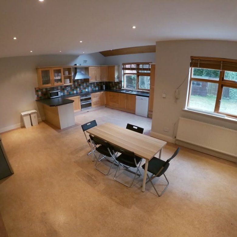 Open-plan kitchen and dining area with wooden cabinets and table setting.