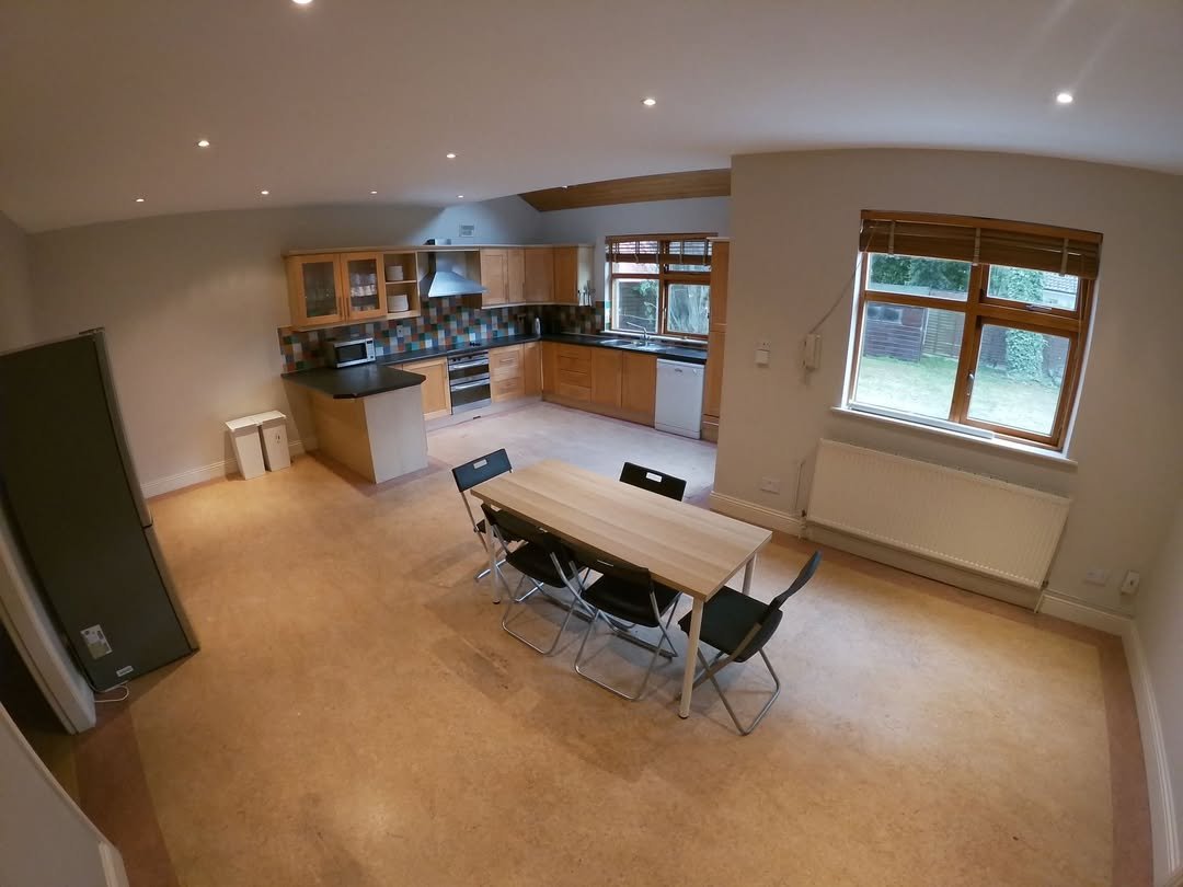 Open-plan kitchen and dining area with wooden cabinets and table setting.
