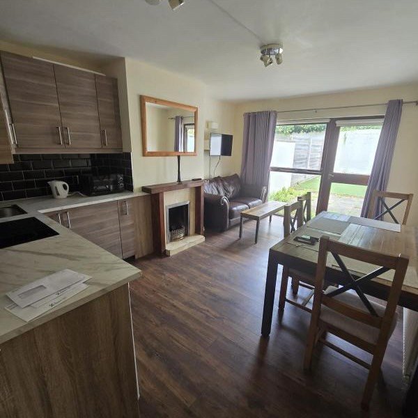 Open-plan living room, kitchen, and dining area with wood floors and natural light.
