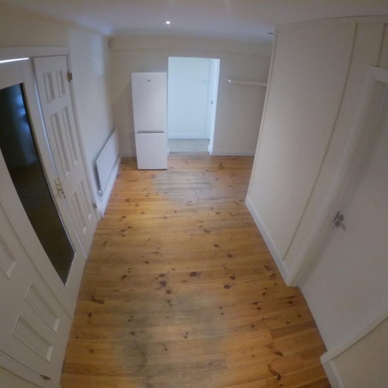 Interior view of a room with wooden floor, white walls, and appliances.