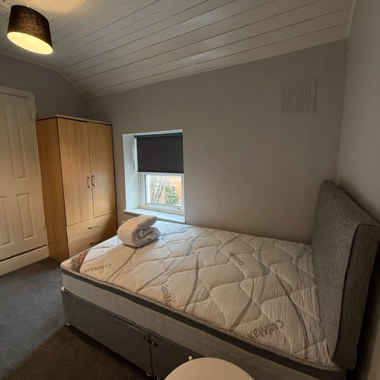 Cozy bedroom with single bed, wardrobe, and small window. Modern interior design.