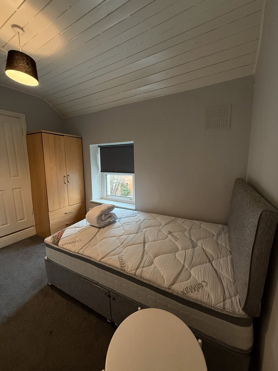 Cozy bedroom with single bed, wardrobe, and small window. Modern interior design.