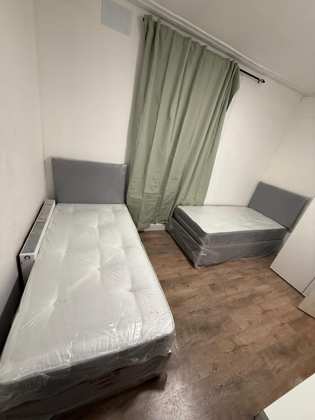 Two single beds with grey headboards in a room.