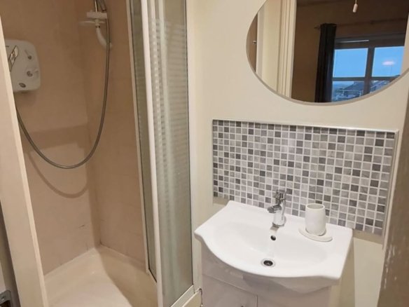 Small bathroom with shower, sink, mosaic tile backsplash, and oval mirror.