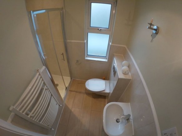 Small bathroom with shower, toilet, sink, and heated towel rack.