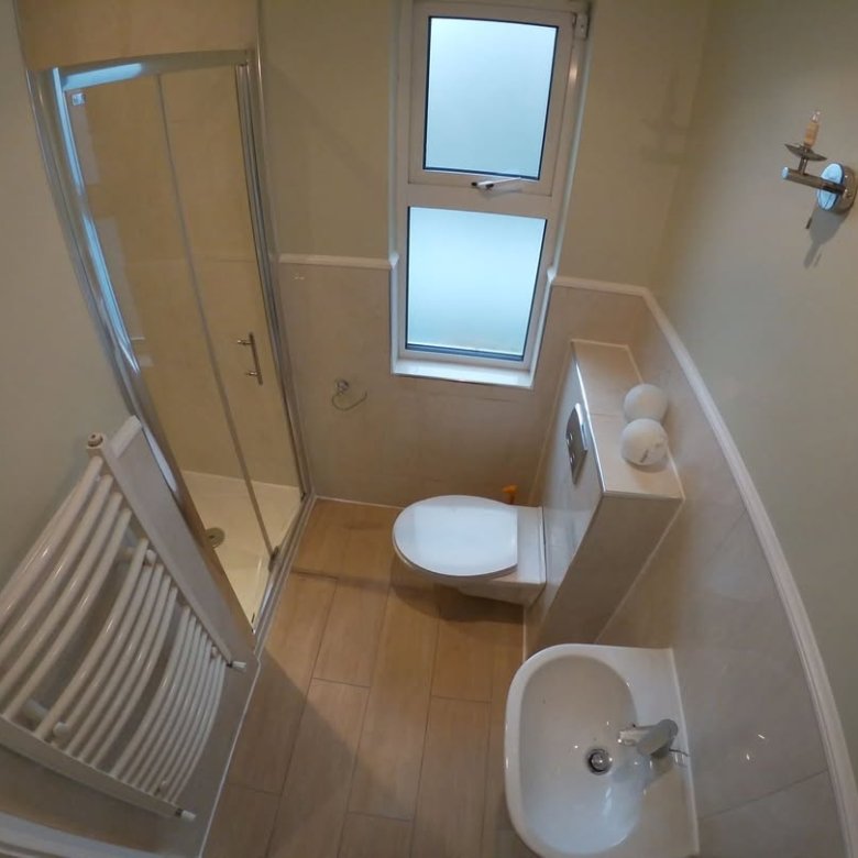 Small bathroom with shower, toilet, sink, and heated towel rack.