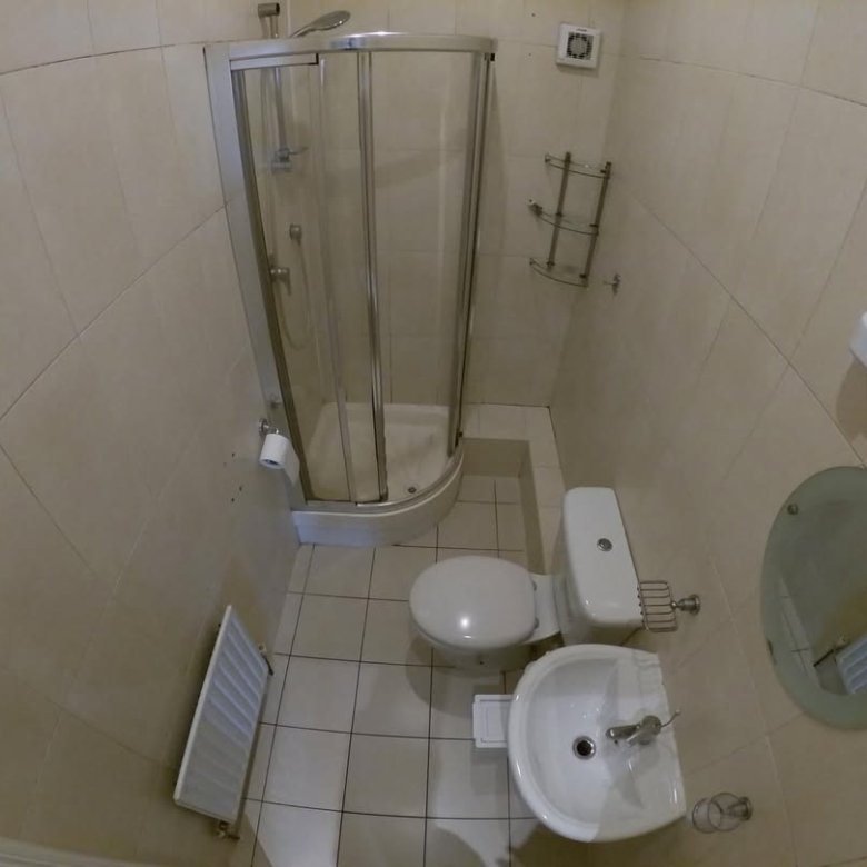 Small bathroom with shower, toilet, sink, and radiator in a compact space.