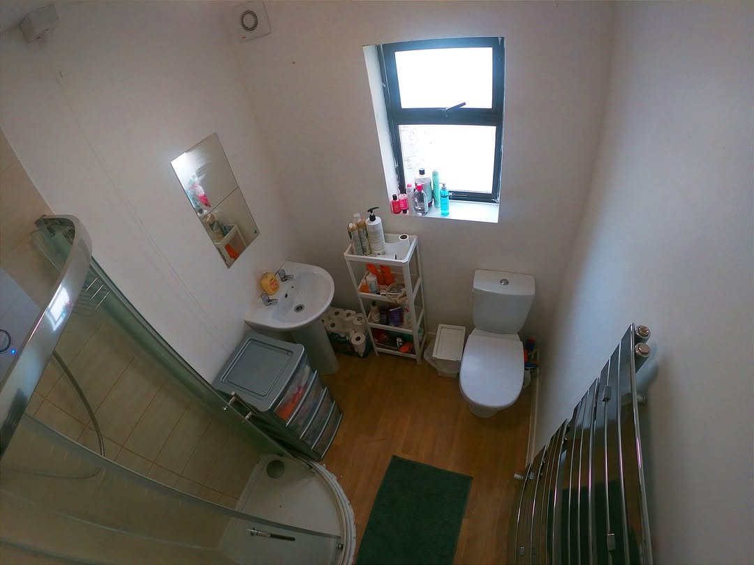 Small bathroom with shower, toilet, sink, and window. Compact and functional design.