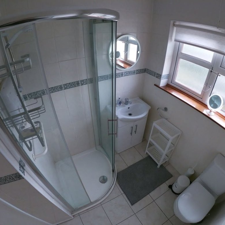 Small bathroom with shower, vanity, toilet, and window for natural light.