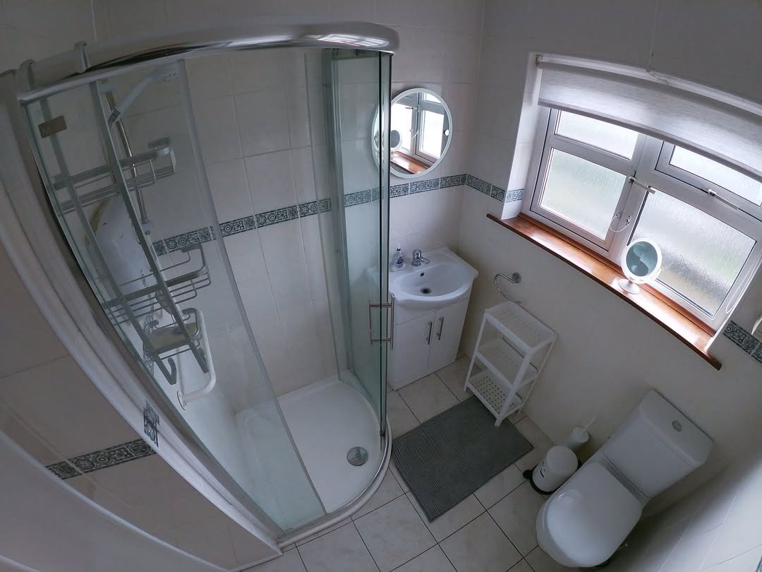 Small bathroom with shower, vanity, toilet, and window for natural light.