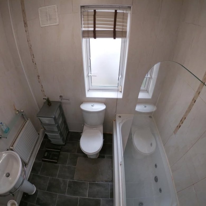 Small bathroom interior with toilet, sink, bathtub, and window.