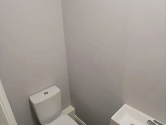 Small bathroom with toilet and sink against gray walls, patterned floor.