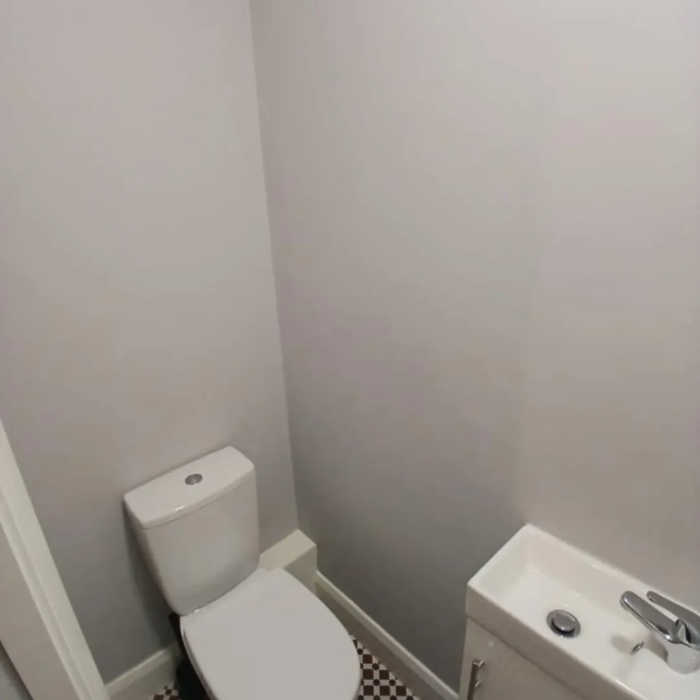 Small bathroom with toilet and sink against gray walls, patterned floor.