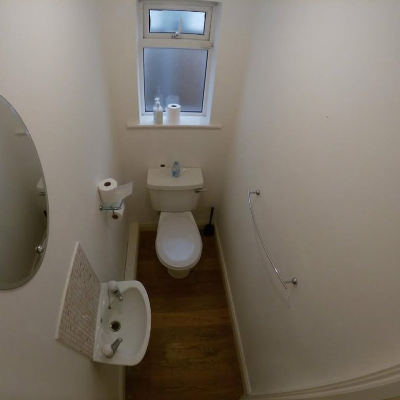 Small bathroom with toilet, sink, mirror, and window.