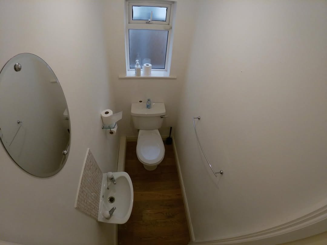 Small bathroom with toilet, sink, mirror, and window.